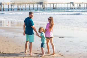 Picture of a family walking on a beach near a pier.
