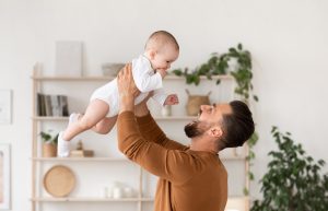 Picture of a father holding a baby in the air in front of him.