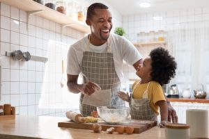 Picture of a father and child cooking together in a kitchen.