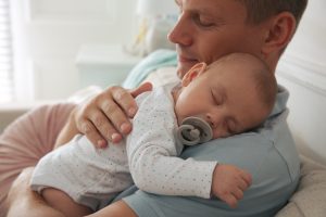 Picture of a man holding a sleeping baby.