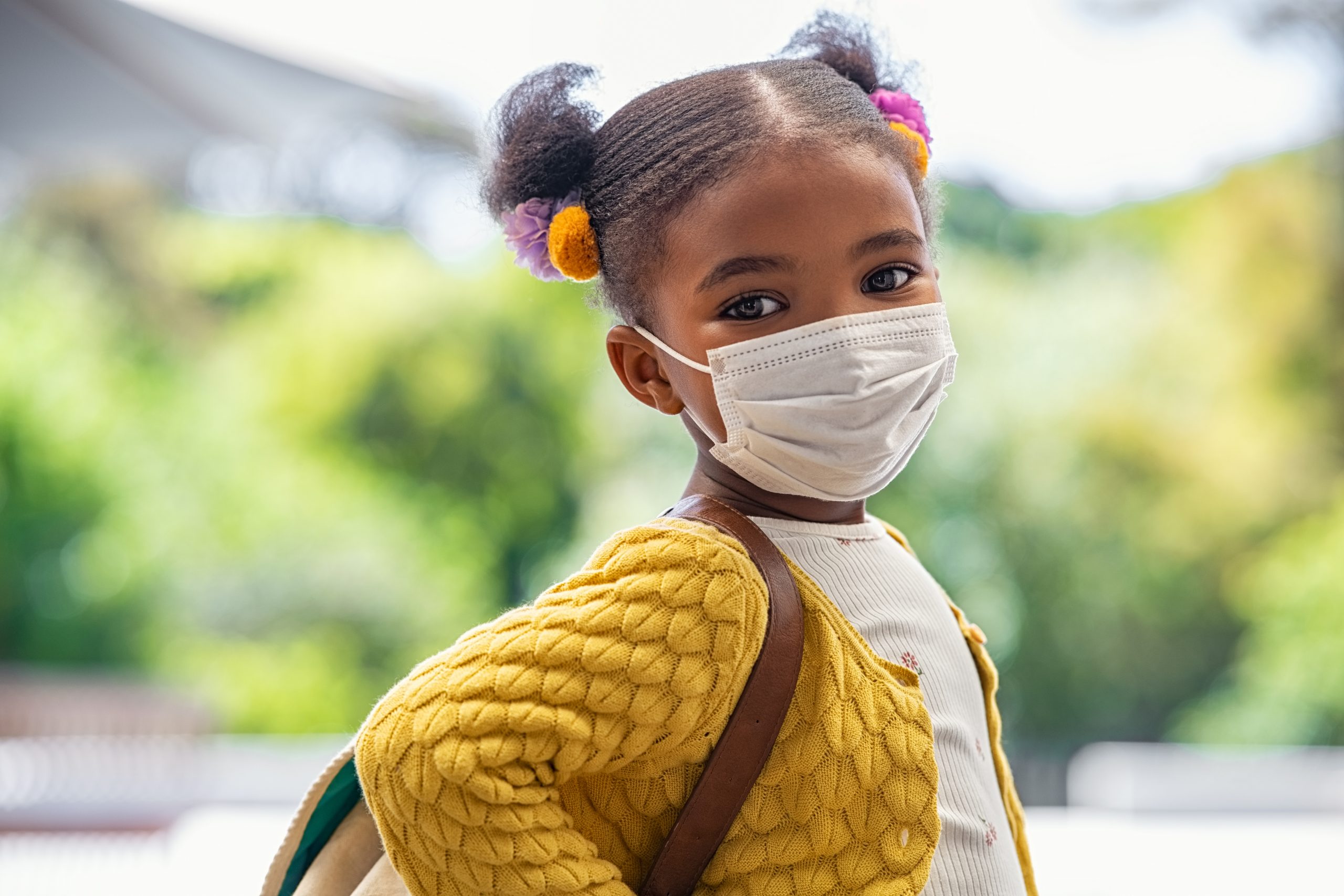 Picture of a young girl wearing a mask and a backpack.