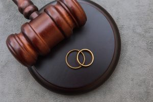Picture of two gold wedding rings sitting on a gavel.