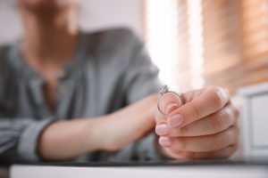 Picture of a woman sitting at a table and holding her wedding ring.
