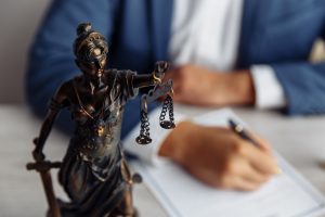 Picture of a family lawyer writing on a piece of paper behind a statue of the scales of justice.