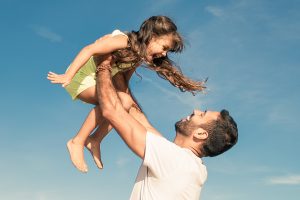 Picture of a father lifting his daughter in the air.