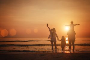 Picture of a family standing on a beach watching a sunset.