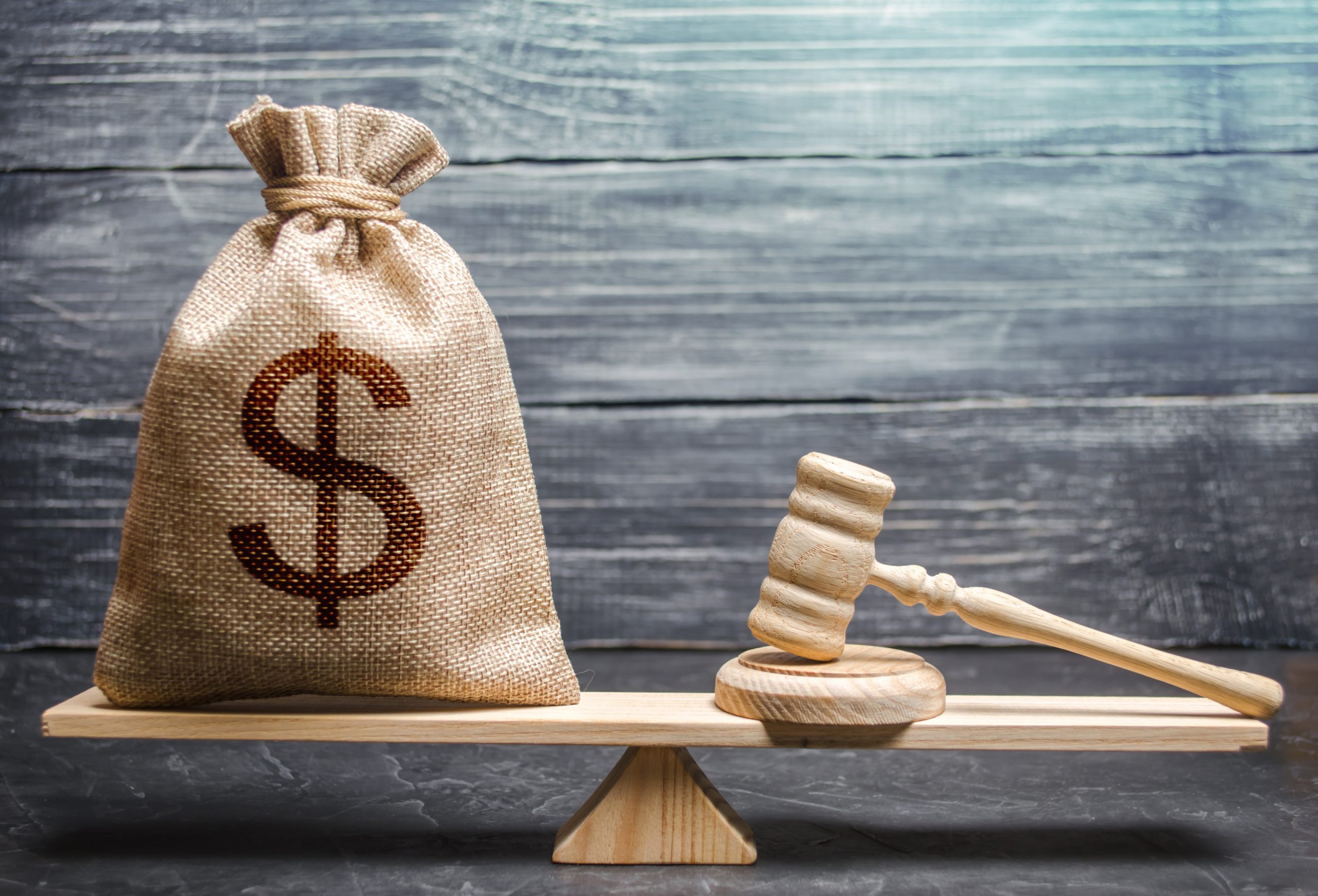 Picture of a bag of money and a gavel sitting on a balance.